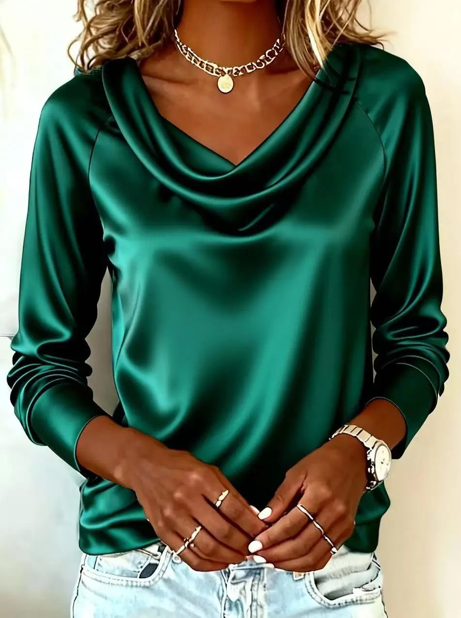 Green satin long-sleeve top worn by a person on a plain background