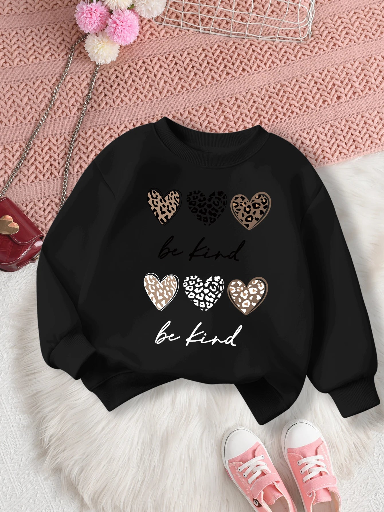 Black sweatshirt with leopard print hearts and 'be kind' text on a Pink textuRed surface.