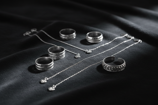 Sterling silver rings, necklaces, and bracelets arranged on dark velvet with soft dramatic studio lighting