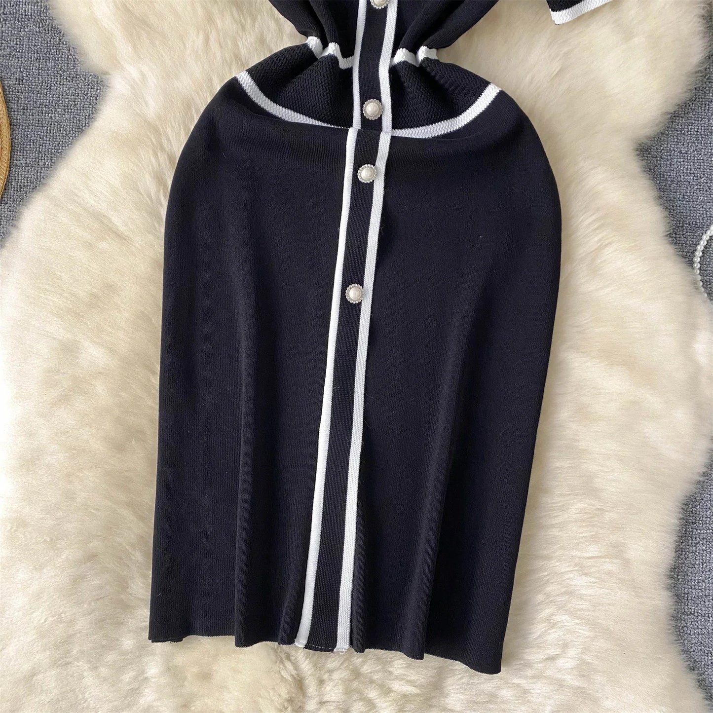 Navy Blue hooded garment with White buttons on a textuRed beige surface