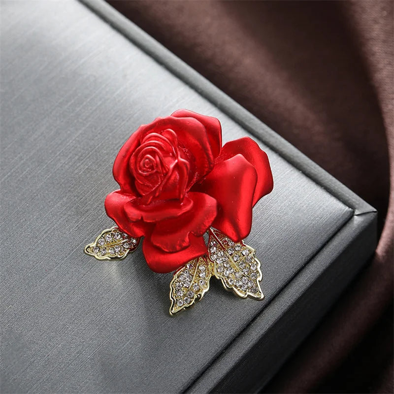 Red rose brooch with gold leaves on a Gray surface