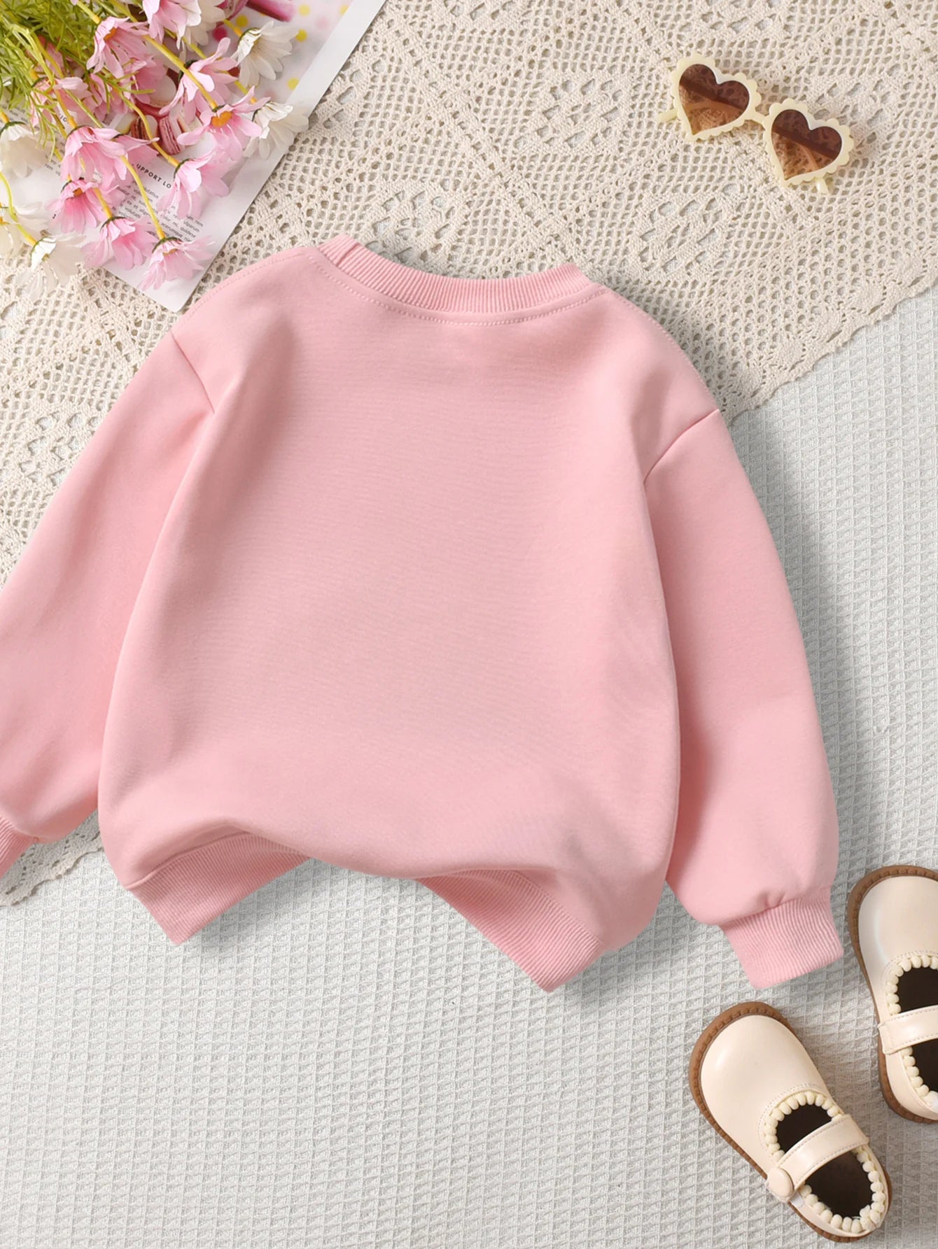 Pink sweatshirt on a textuRed surface with decorative elements