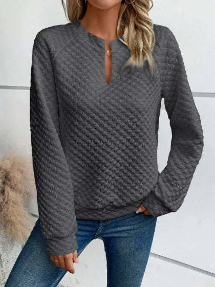 Person wearing a textuRed Gray sweater and Blue jeans against a neutral background