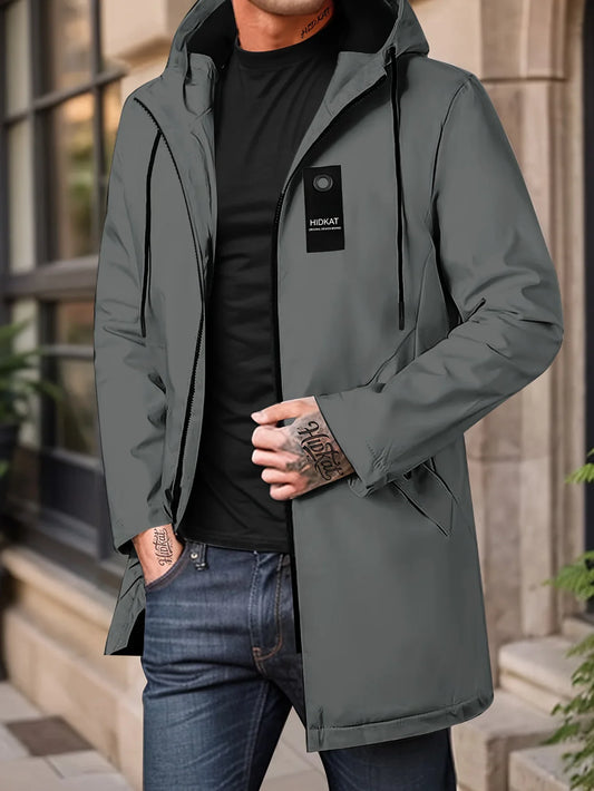 Person wearing a Gray jacket with a brand logo, standing outdoors.