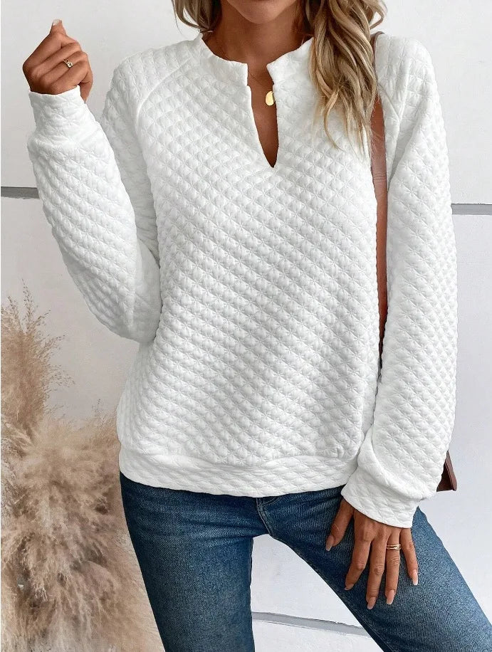 White textuRed long-sleeve top worn by a person with a neutral background