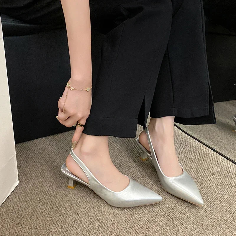 Person wearing silver high-heeled shoes on a neutral background