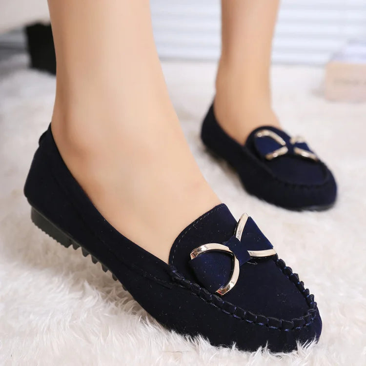 Navy loafers with a gold buckle on a White surface
