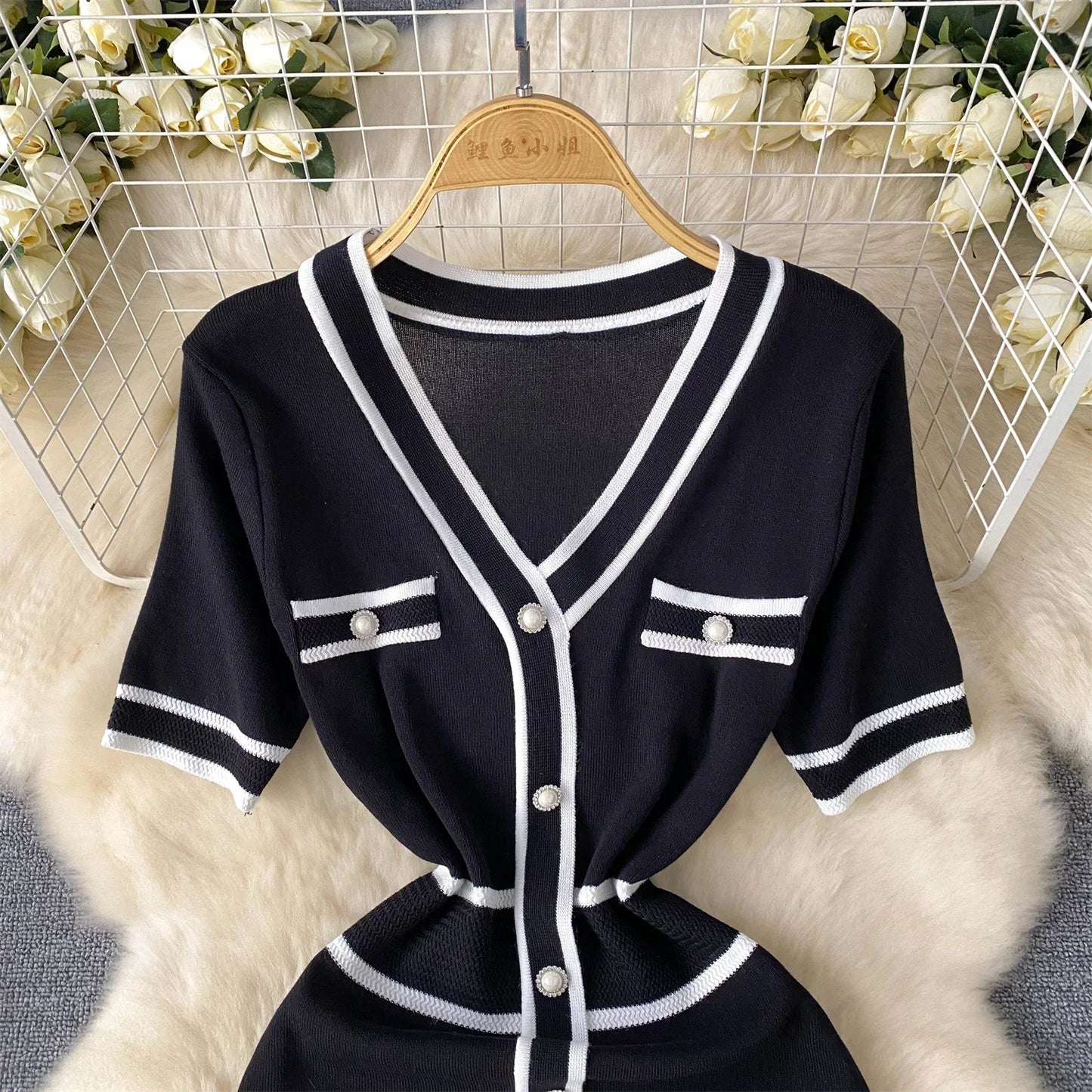 Black and White outfit with buttons on a hanger against a floral background