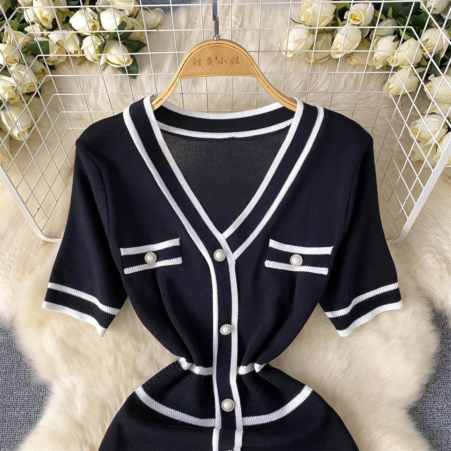 Black and White outfit with buttons on a hanger against a floral background