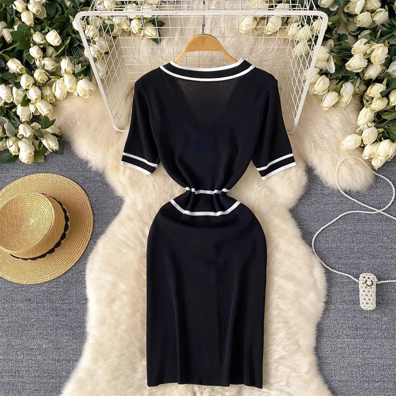 Black dress with White trim on a hanger against a floral and textuRed surface background