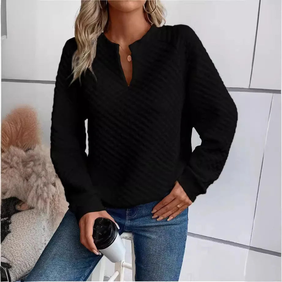 Person wearing a Black sweater and Blue jeans, holding a coffee cup indoors.