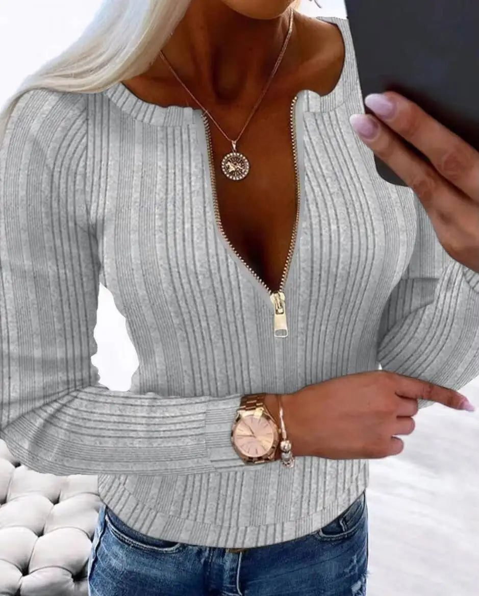 Person wearing a Gray ribbed sweater with a zipper detail, holding a phone.