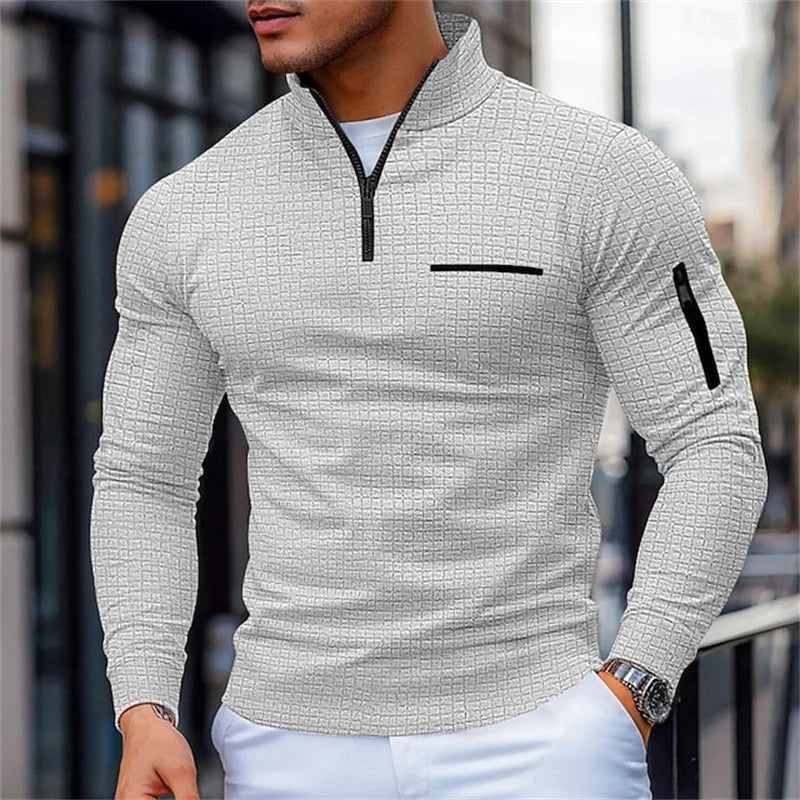 Man wearing a Gray textuRed sweater with Black zipper and pocket details, standing outdoors.
