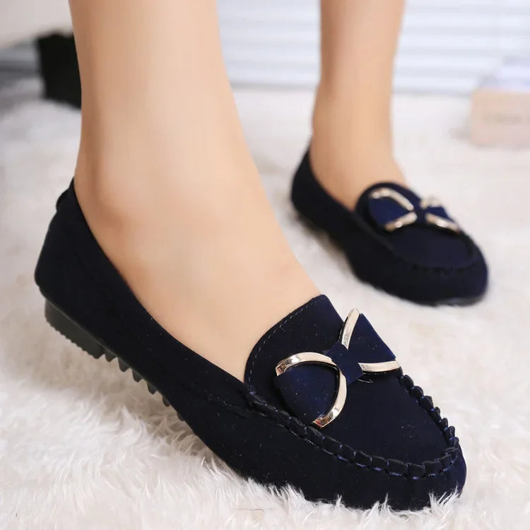 Navy loafers with a gold buckle on a White surface