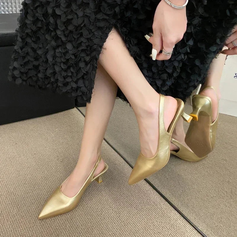 Gold high-heeled shoes worn by a person sitting on a couch.