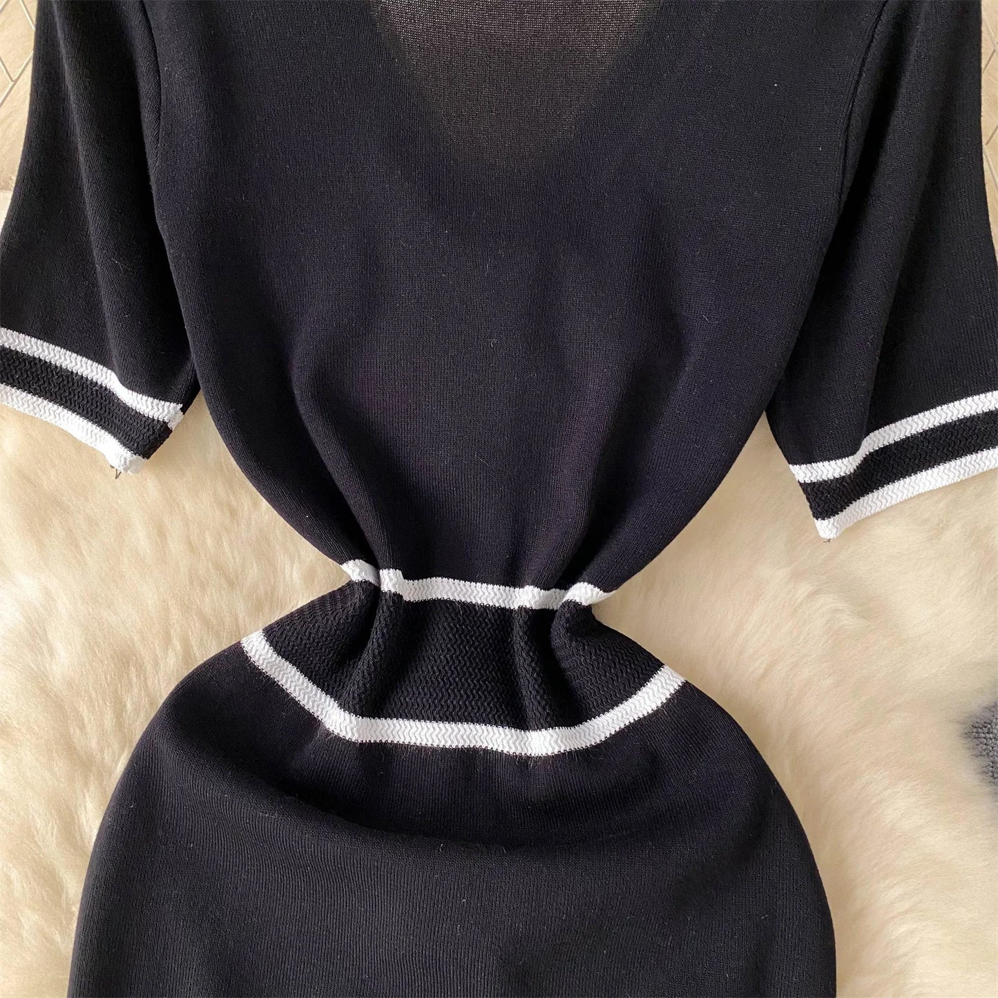 Black dress with White trim on a beige surface