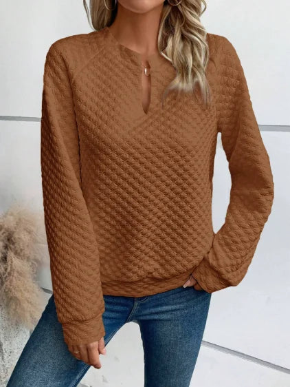 Person wearing a Brown textuRed sweater and Blue jeans against a White background