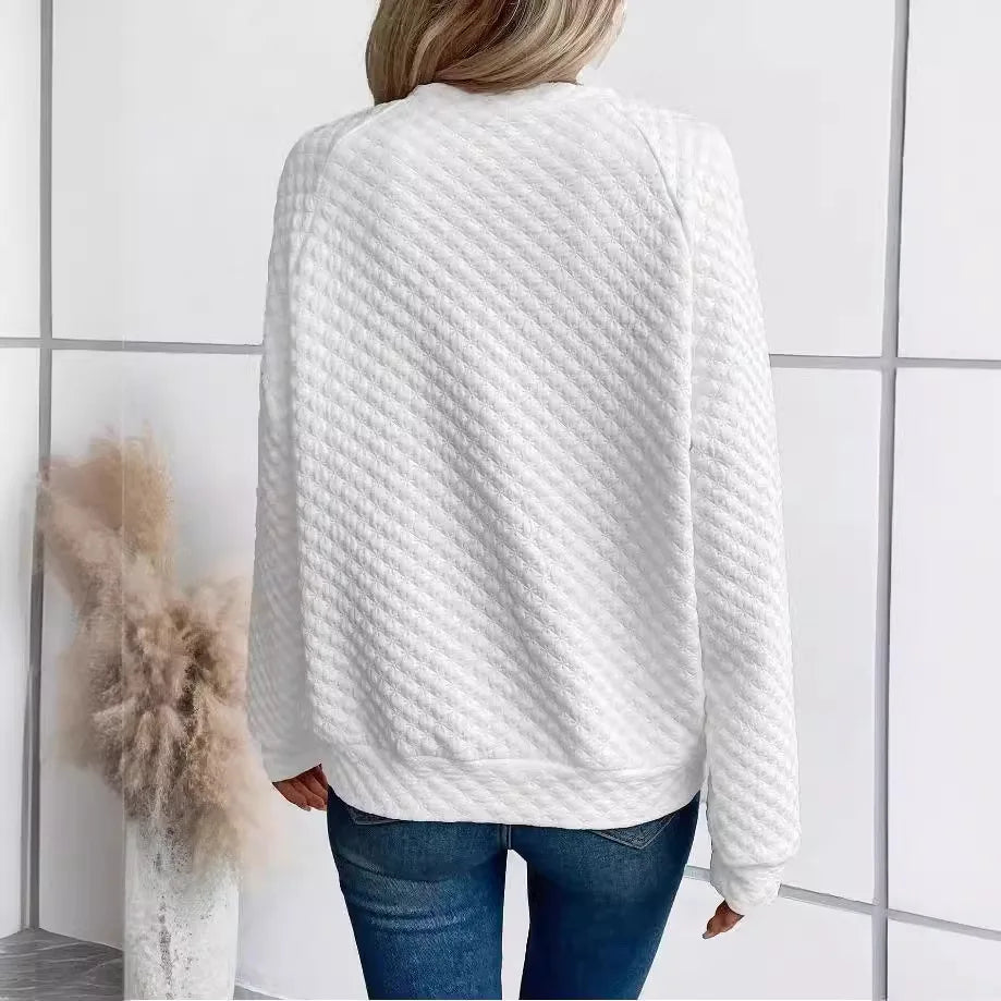Person wearing a textuRed White sweater and Blue jeans in a minimal indoor setting.