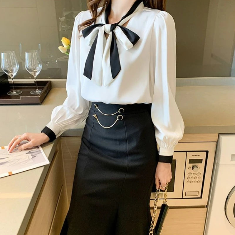 Woman in a White blouse with a Black bow tie and Black skirt in a kitchen.