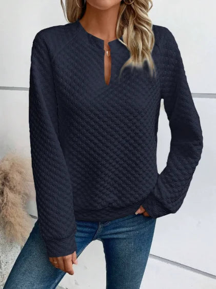 Person wearing a textuRed navy sweater and jeans against a neutral background