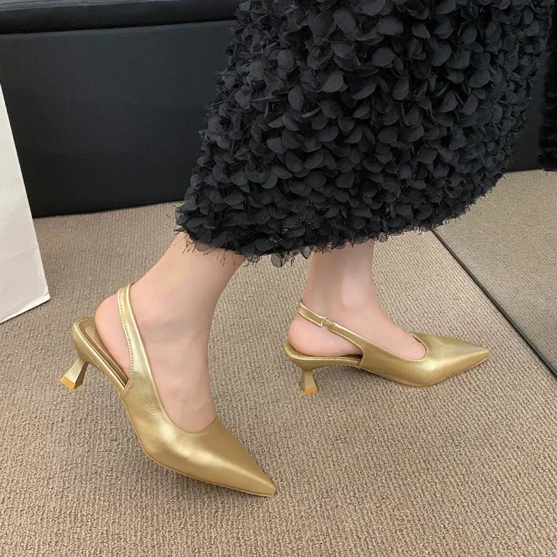 Gold high-heeled shoes worn with a Black textuRed skirt on a carpeted floor.