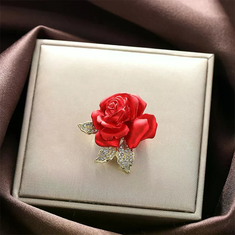 Red rose brooch with diamond-like stones on a beige jewelry box