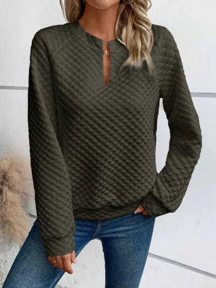 Person wearing a textuRed Green sweater and Blue jeans against a neutral background