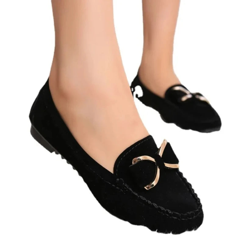 Black loafers with gold accents worn by a person on a White background