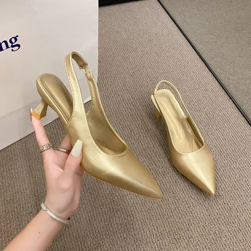Gold high-heeled shoes on a textuRed surface with a hand holding one shoe.