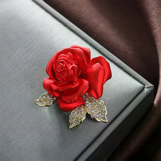 Red rose brooch with gold leaves on a Gray surface