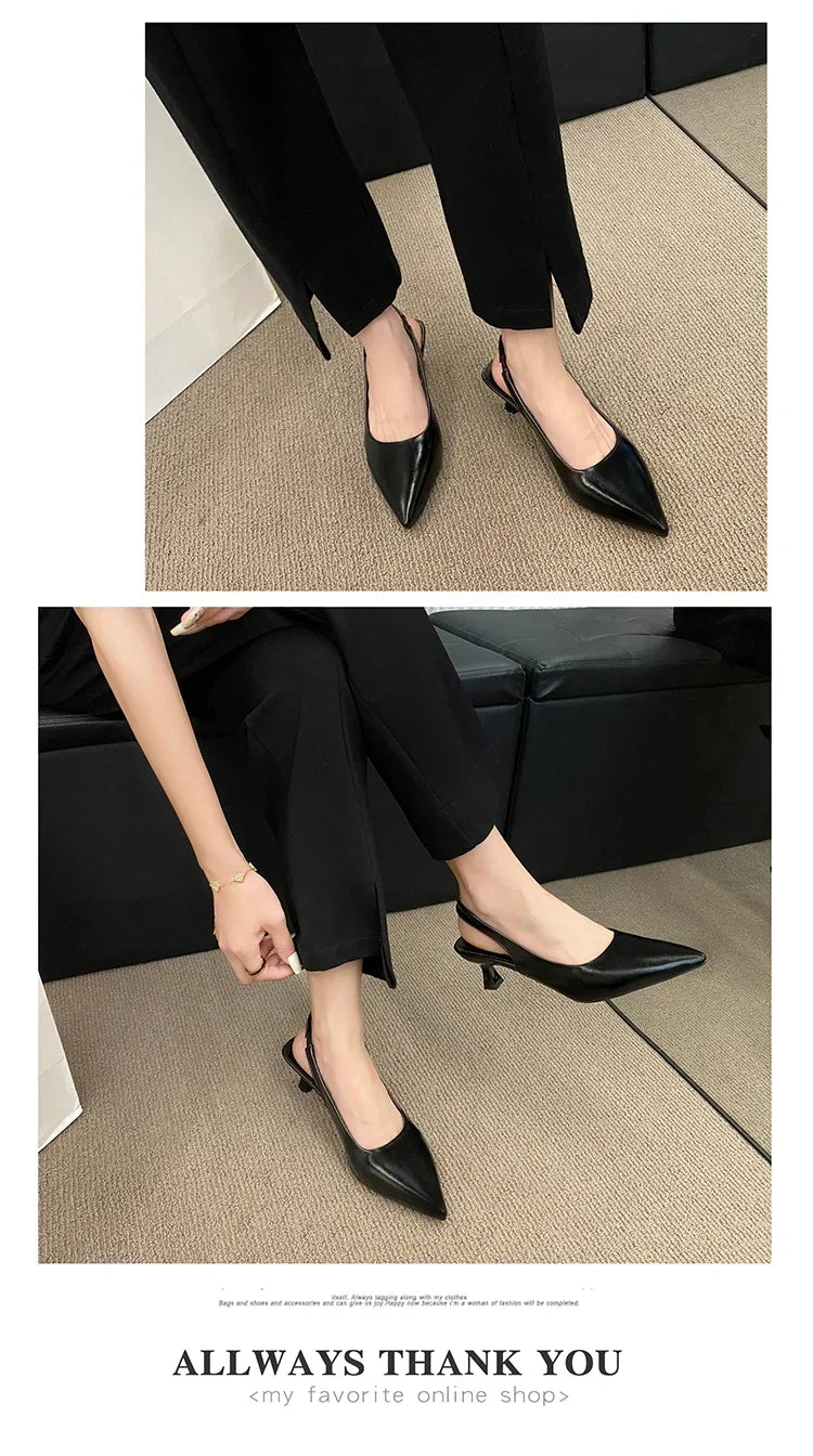 Black pointed-toe shoes worn by a person sitting on a couch.
