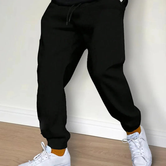 Person wearing Black sweatpants and White sneakers on a light wooden floor.