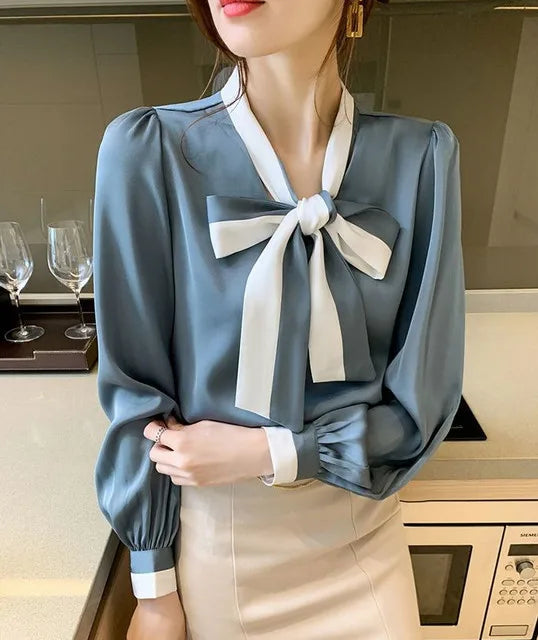 Woman wearing a Blue blouse with a large bow tie in a kitchen setting