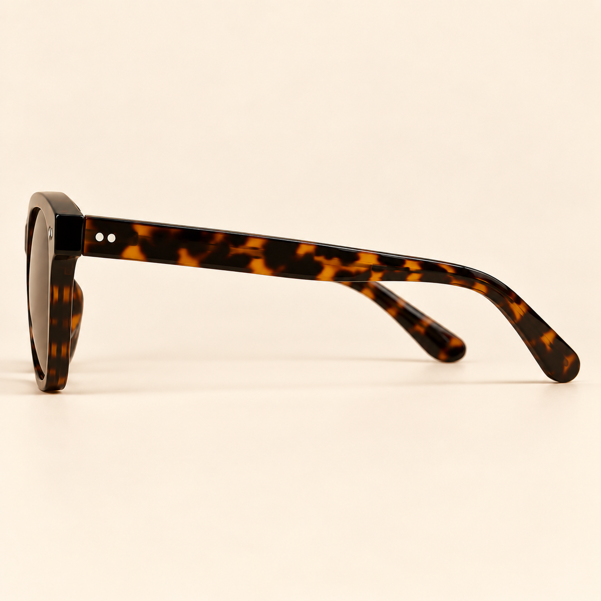 Vintage tortoiseshell sunglasses side profile on warm cream background